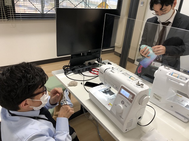ミシンを使ってオーナメントを製作する男性2名