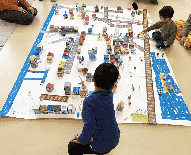 ペーパークラフトのまちづくりキットで遊ぶ子供たち