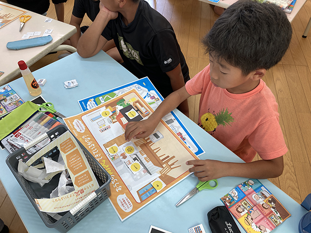 キッチンでの防災対策を行うためのパーツを切っている子どもたちの様子