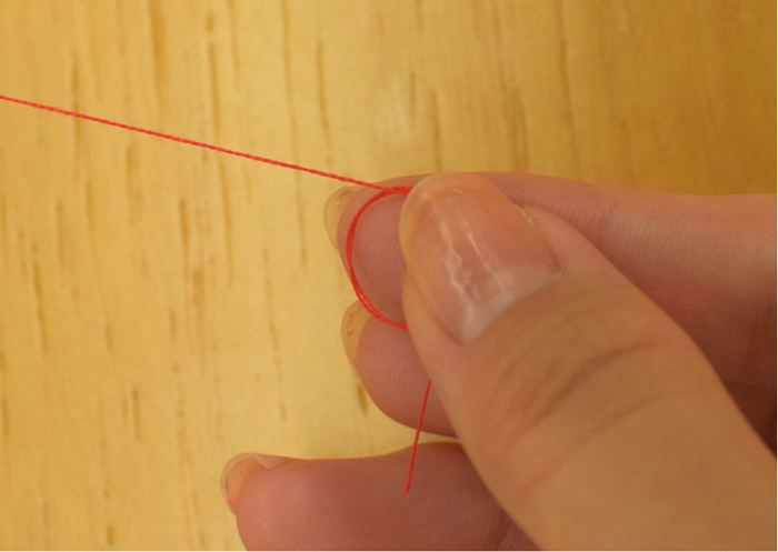 3.人差し指から糸を外し、交差した部分を親指で押さえたまま、糸を引っ張ります。