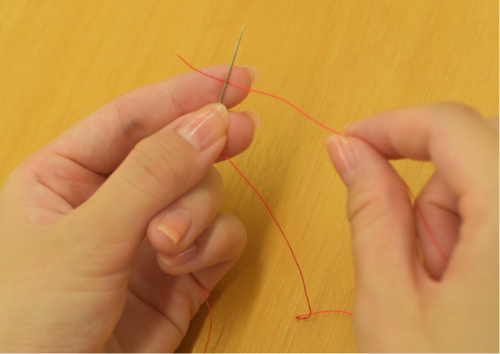 1.針に糸を通したら糸端から2cmぐらいのところをつまみ、針を持っている手の人差し指に乗せ、針を当てます。
