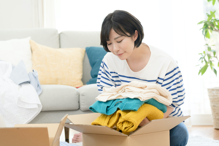 服を箱に入れている女性の写真