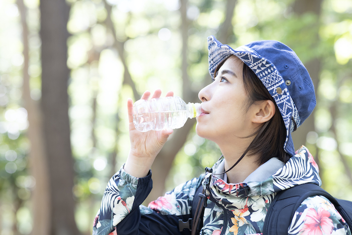 登山中に水筒で水を飲む女性