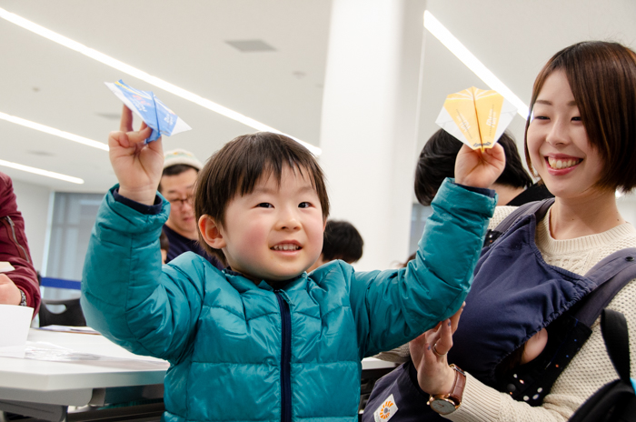 完成した紙飛行を持つ親子