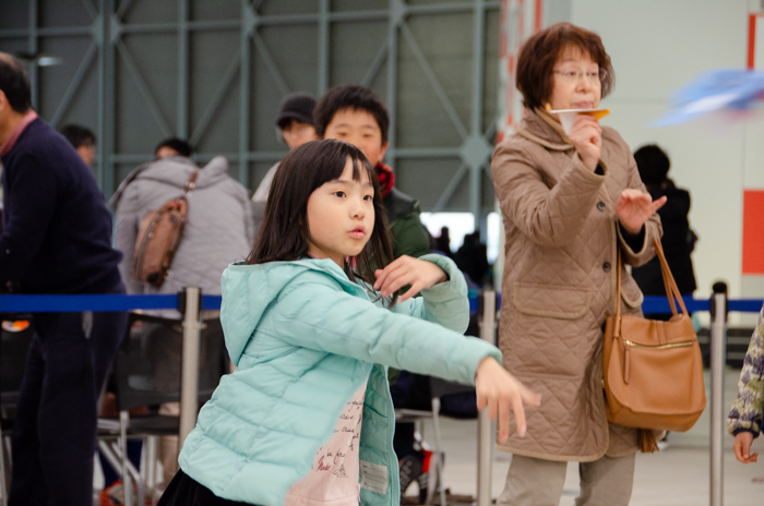 遠くをめがけて紙飛行機を飛ばす子どもたち