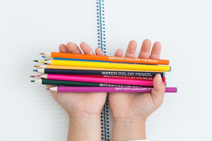 複数の色鉛筆を持つ子供の両手