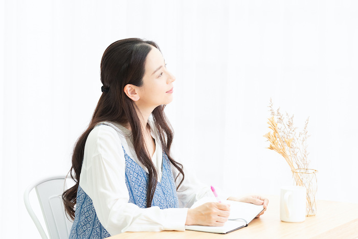 机に向かってメモを取る女性